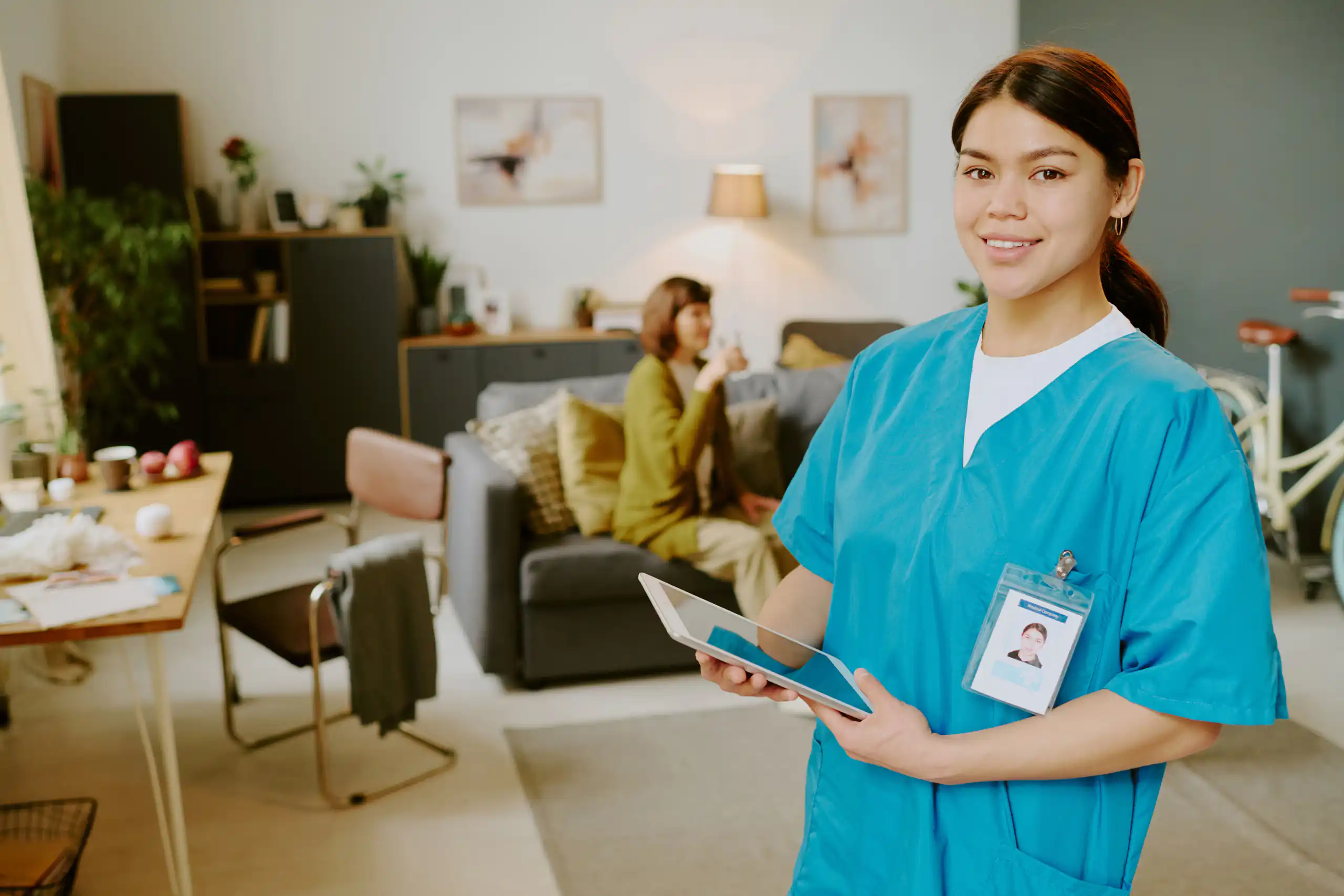 A healthcare worker holding a tablet in a living room