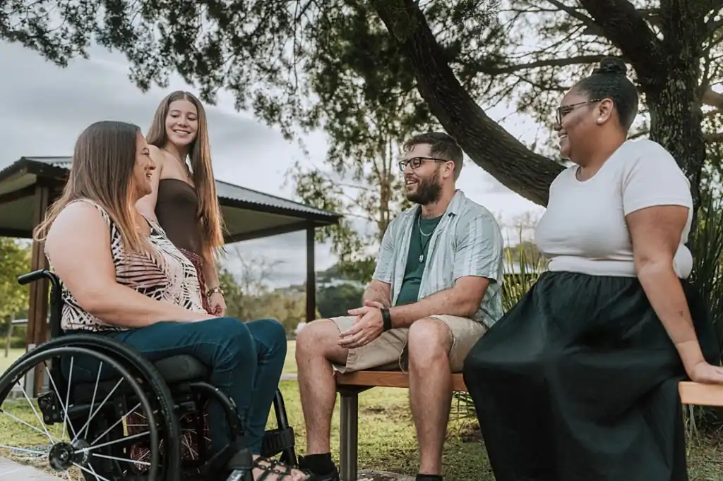 Friends talking together at an outdoor table, illustrating community access support on the sunshine coast.