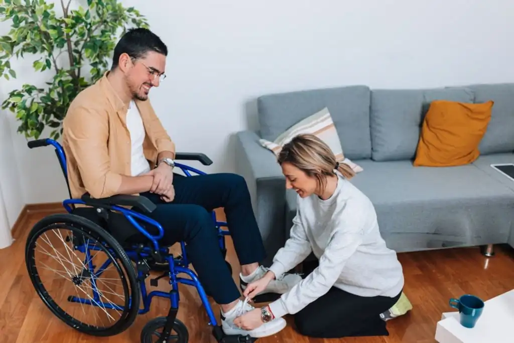 A person helping someone put on footwear, illustrating disability support services in moreton bay.